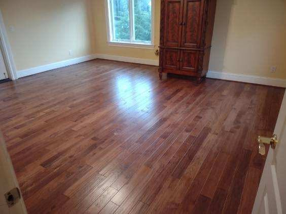 Warm walnut-toned hardwood flooring in a bright bedroom with an antique armoire