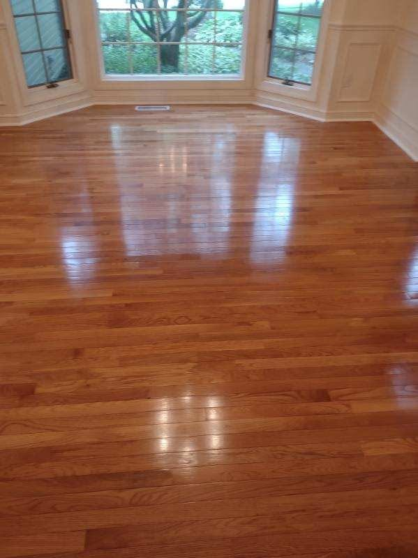 Glossy golden oak flooring beside a bay window with white trim and baseboards